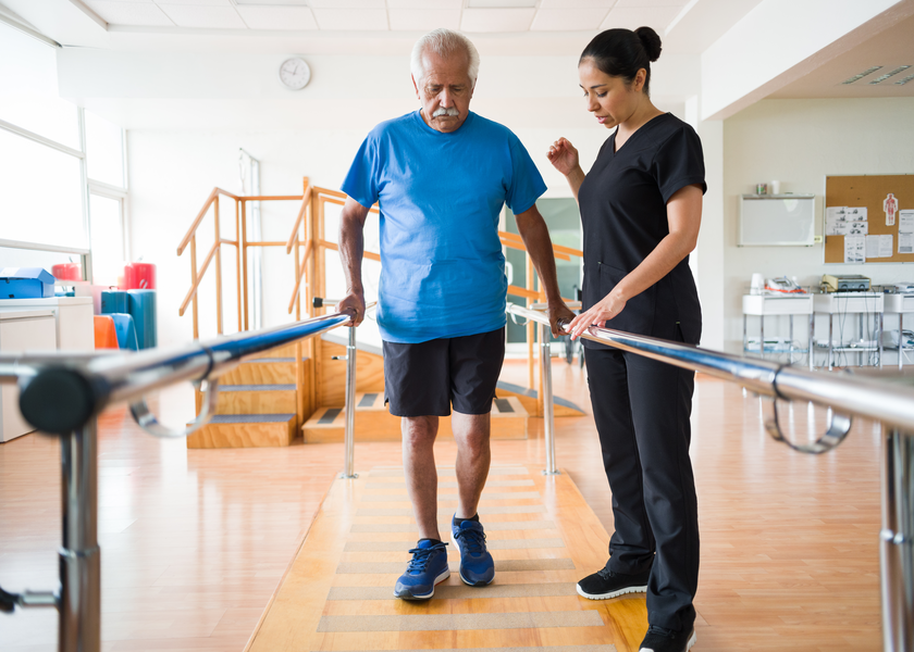 Senior man with nurse performing physical therapy 