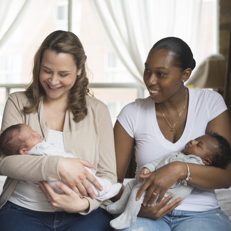 Group of moms are seated and cradling their newborns