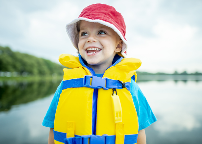 little boy wearing life jacket on a dock