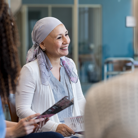 Woman battling cancer smiles while surrounded by others.