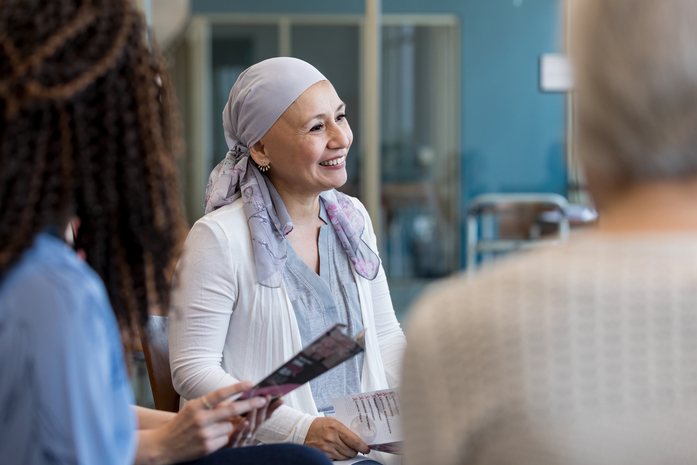 Woman battling cancer smiles while surrounded by others.