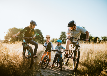 Family riding bikes together in foothills. 