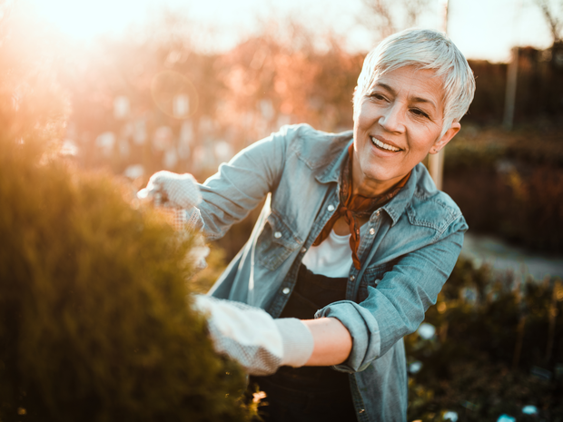 Woman smiles while tending to her garden outdoors.