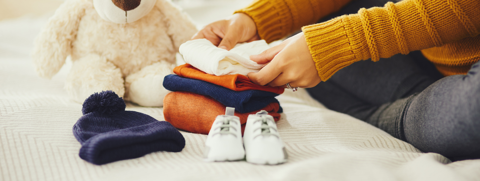 mom lovingly fold infant clothing