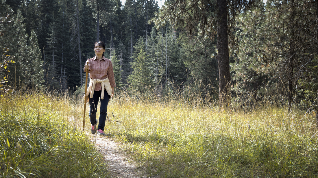 Woman on hike outdoors with walking stick.