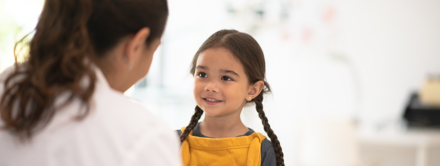 A little girl in braids in yellow overalls. 
