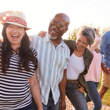 Group Of Mature Friends On Vacation Walking Along Path Through Campsite At Sunset