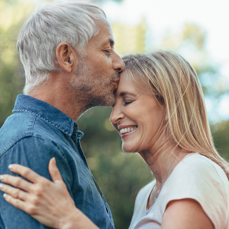 Mature man kissing his wife on her forehead outside