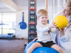 physical therapist works with young boy