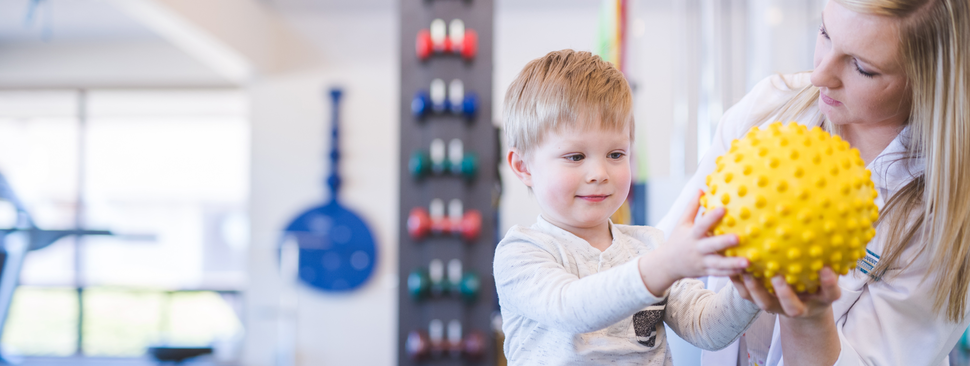 physical therapist works with young boy