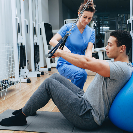 A man being worked on with a nurse against a yoga ball