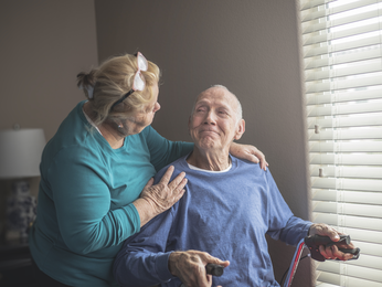 Man embraced by his partner at home.