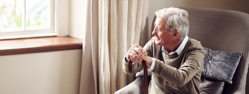 A senior man sits near a window