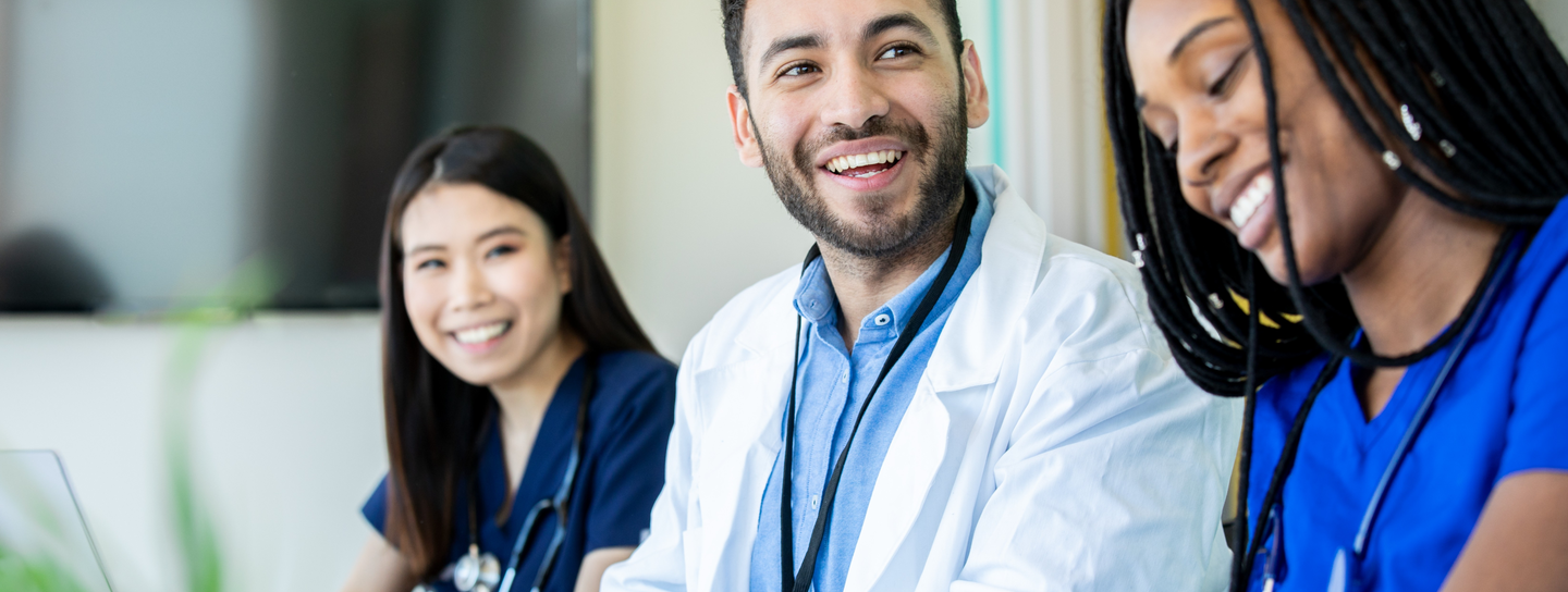 Student nurses sit at a desk working and collaborating together