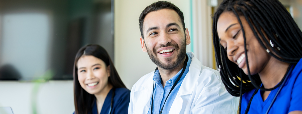 Student nurses sit at a desk working and collaborating together