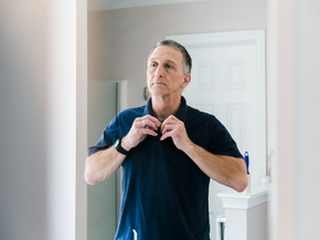 Mature man buttoning his shirt