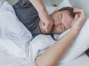 A man coughing in bed