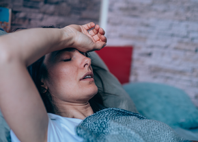 A woman lays in bed in distress