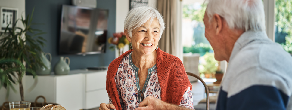 Smiling senior woman talking with her husband during breakfast