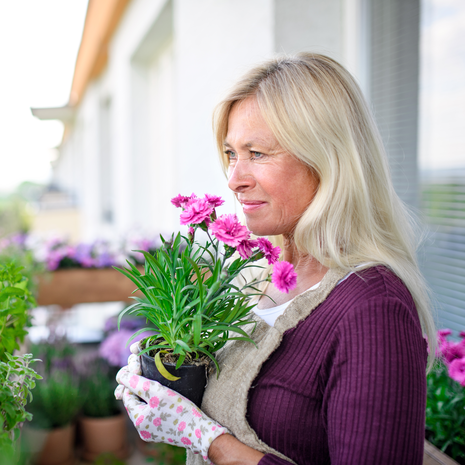 Mature woman smelling the flowers on her balcony