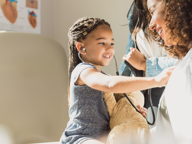 Girl using stethoscope on pediatrician.