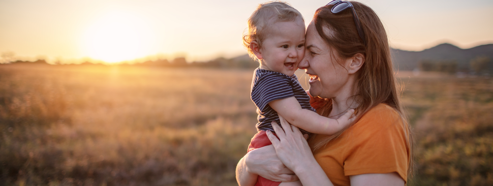 Mom hugging her baby in a field