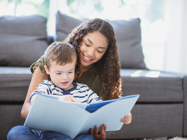 Girl reading book with toddler.