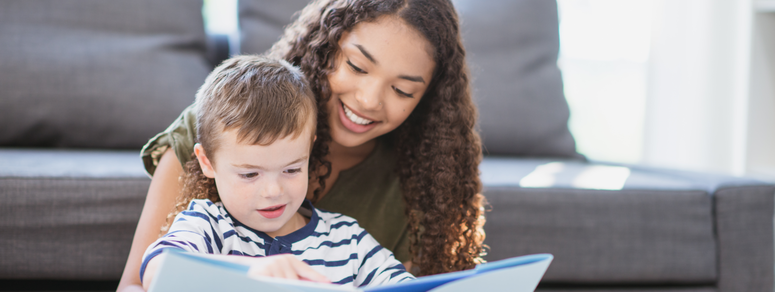Girl reading book with toddler.