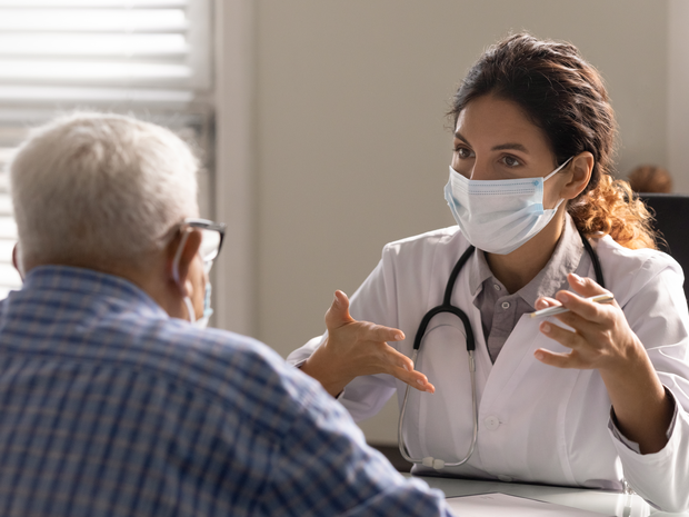 Doctor talking to male patient in doctor's office.