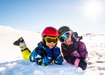 two children laying in the snow.