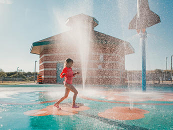 Young girl running through splash pad