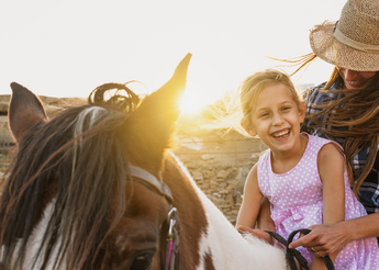 Mother and daughter riding together on horeseback.