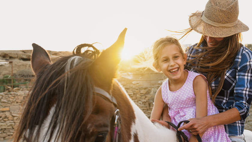 Mother and daughter riding together on horeseback.