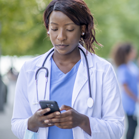 A doctor uses her mobile phone outside.