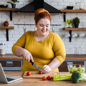 A woman in yellow cutting vegetables.