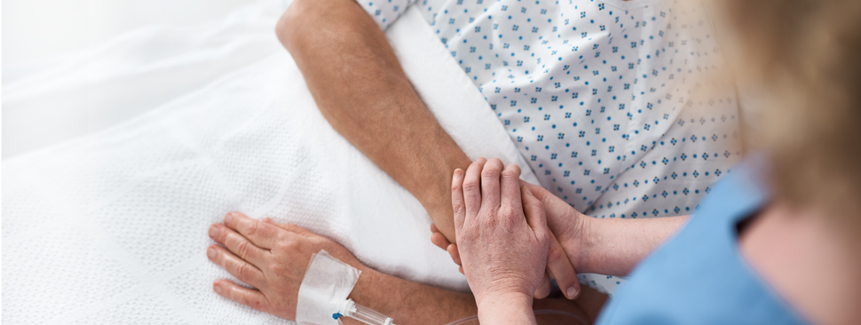 Woman holding hands of hostipal patient.