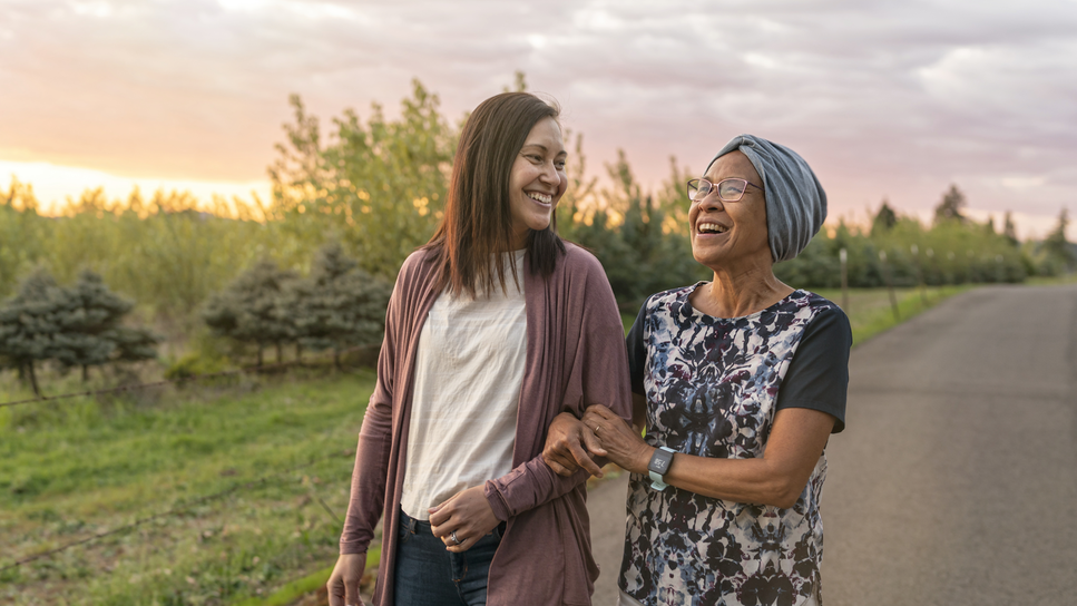 Two women walking outside together, smiling.