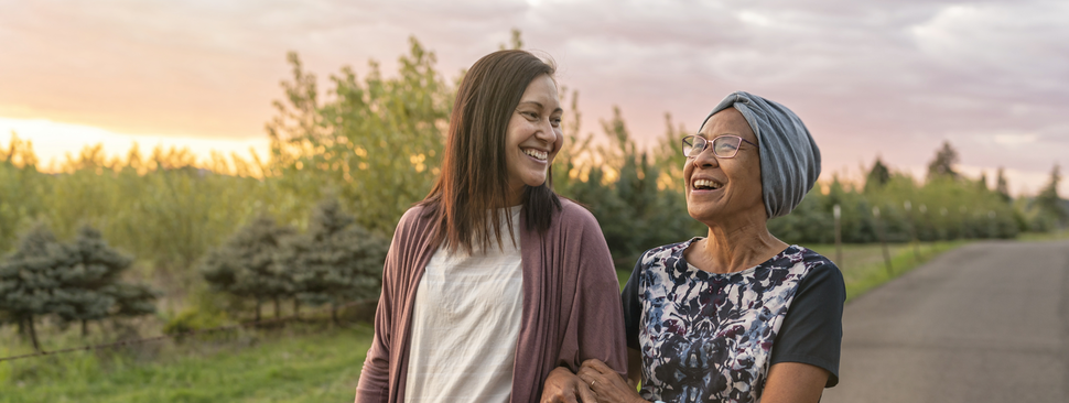 Two women walking outside together, smiling.