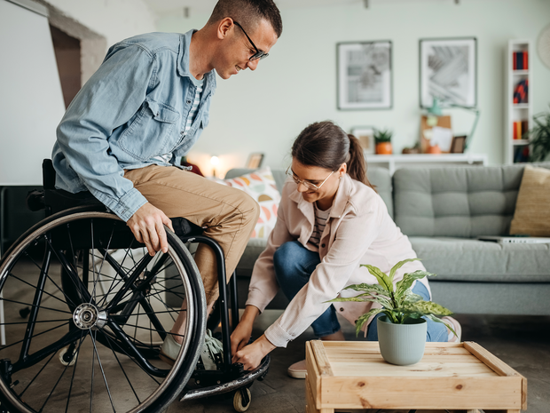 Woman helps her husband with a disability to sit in a wheelchair
