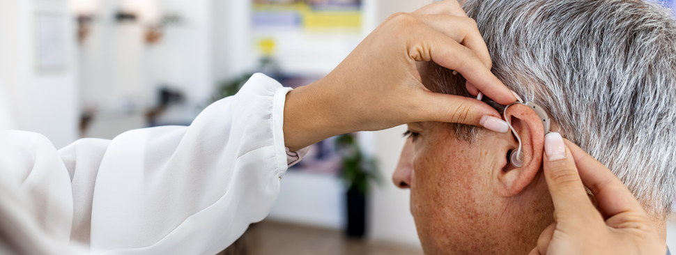 An older man gets a hearing aid fitted.