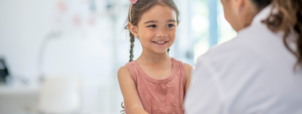 A young girl smiles as she talks to a doctor