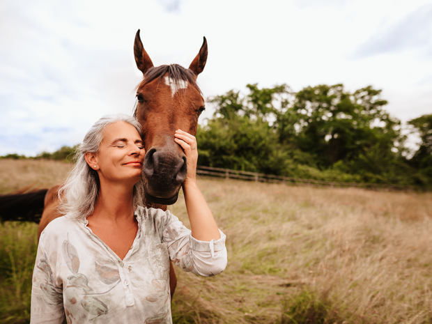 Beautiful mature woman petting a horse