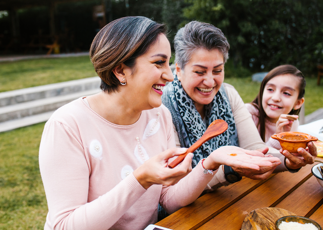 Las mujeres hispanas sonríen mientras comen al aire libre.