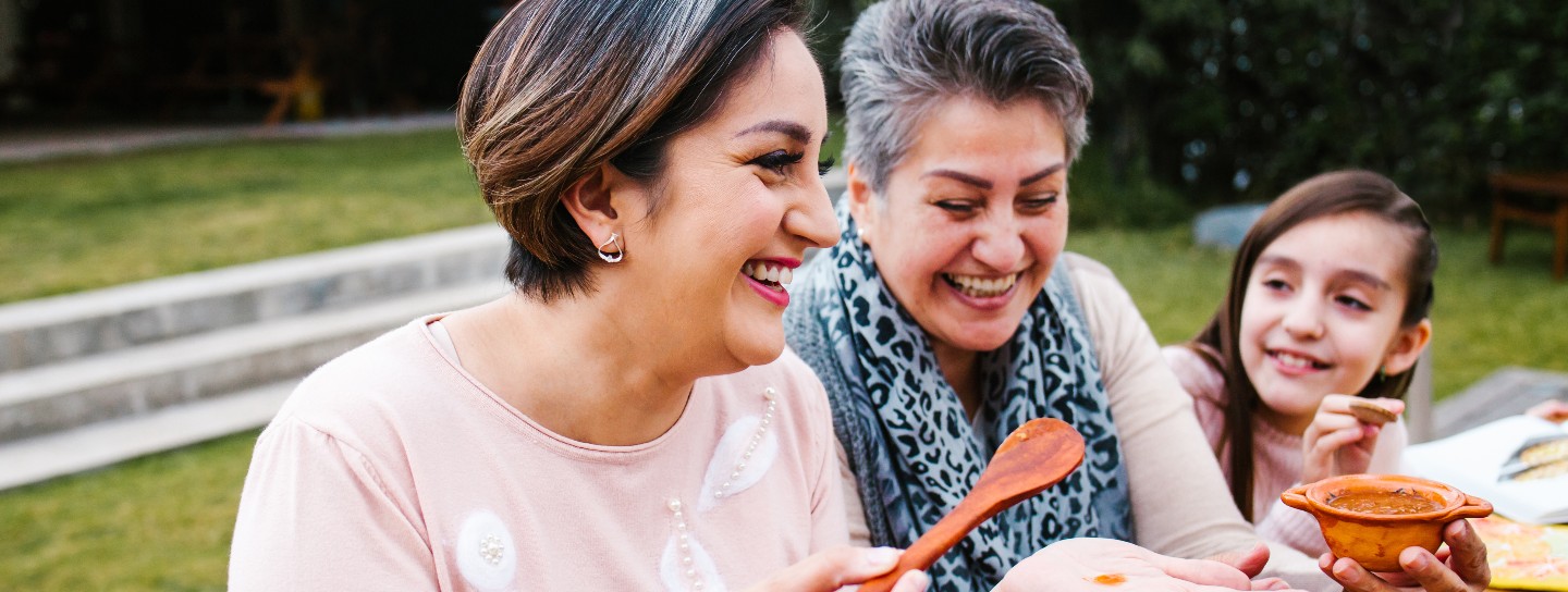 Latin grandmother and granddaughter, daughter cooking mexican food at home