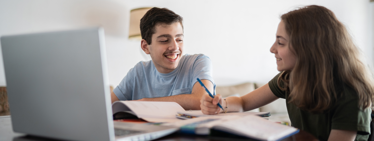 Teen boy getting help from his mother with online homework