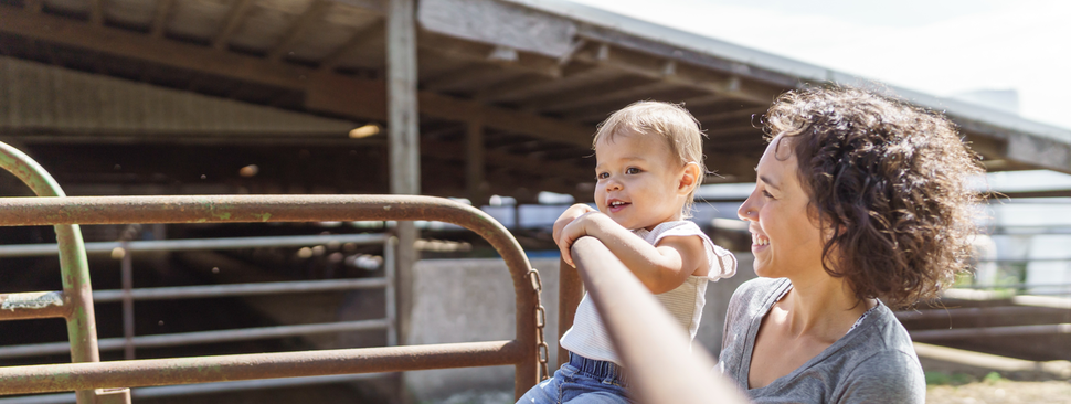 Woman and her toddler on gate near stock pens.