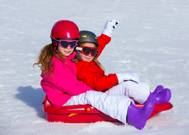 Two girls sledding.