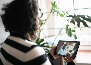 A woman video-calls her doctor using a tablet