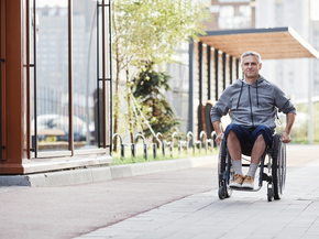Mature man with disability riding in wheelchair outdoors
