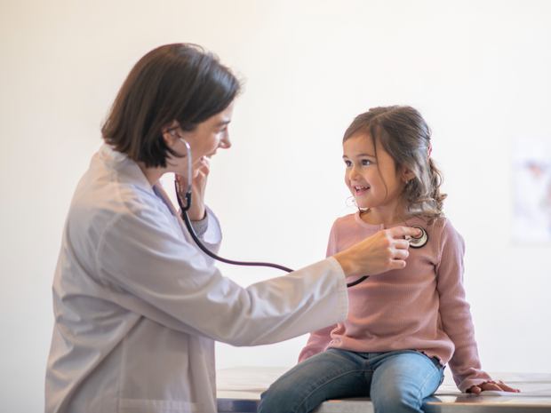 Doctor listens to young girl’s heart.